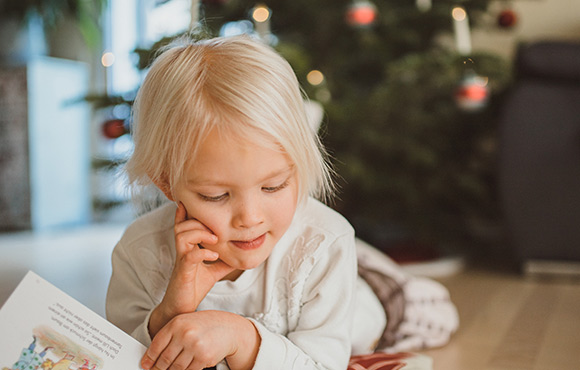 Blogbeitrag Advent Kind liegt vor Weihnachtsbaum